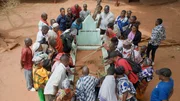 Die Protagonisten John Mbano, Aidan Mbano und ihre Familie gedenken dem ermordeten Songea Mbano an dessen Grab.
