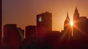 Dieses Bild zeigt einen Sonnenuntergang hinter der Skyline von New York.