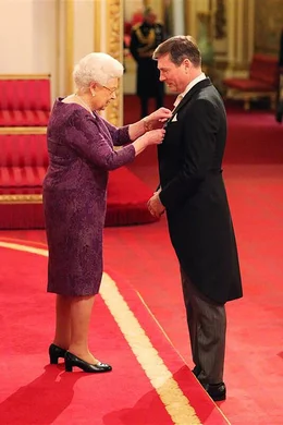 Die Queen verleiht Stewart Parvin 2016 den Hausorden, Royal Victorian Order, in Anerkennung seiner Dienste. Zwei Jahrzehnte lang war der Modesch&ouml;pfer f&uuml;r den Look der K&ouml;nigin verantwortlich.