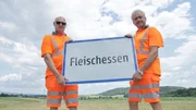 Mitarbeiter der Stra&szlig;enmeisterei Mank halten die Ortstafel von Fleischessen.