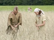 Olli Junker-Matthes und seine Frau Britta bei der Feldarbeit, im Hintergrund spielen die Kinder.
