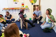 Mona Vetsch (r.) mit Sozialp&auml;dagoge Lukas Zimmermann (mit Gitarre) beim Singen mit den Kindern.