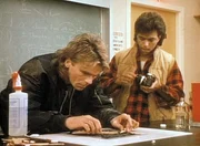 MacGyver (Richard Dean Anderson, r.) und Tony (Glenn Scarpelli, l.) versuchen, auf einem verkohlten Blatt Papier die Schrift zu entziffern.