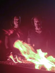 The Gibbons twins standing behind a fire.