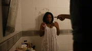 Yvette in the bathroom covered in blood with a man pointing a weapon at her.