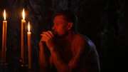 Bill not wearing a shirt in front of candles.