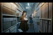 Paula (Fine Sendel) sucht im Archiv des Instituts nach einem Flashback ihres verstorbenen Hauptfigurenvaters.