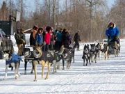 Kathleen Zuray (L) waves, as Mike Buser (R) arrives. He's the first musher to cross the checkpoint.