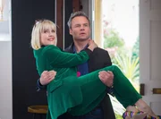 James Lacey (Jamie Glover) gratuliert Agatha Raisin (Ashley Jensen) zu ihrer bestandenen Pr&uuml;fung als Privatdetektivin.