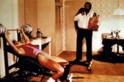 Steve (Bud Spencer, r.) und seine Kollegin, die FBI-Agentin Irene (Jackie Castellano, l.), halten sich auf unterschiedliche Weise fit: Steve isst w&auml;hrend Irene trainiert ...