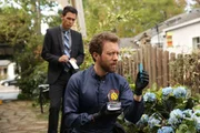 Agent Aubrey (John Boyd, l.) begutachtet Hodgins (TJ Thyne) Fund im Garten des Opfers: Handelt es sich um Knochen des ermordeten Collegeprofessors?