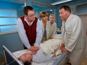 Als Hans-Peter Brenner (Michael Trischan, links) seiner Mutter sagt, dass er die Stelle in der Klinik wieder gek&uuml;ndigt hat, um sich um sie zu k&uuml;mmern, kommt es zum Streit und Luises (Monika Lennartz, liegend) Zustand eskaliert. Brenner schickt Schwester Yvonne (Maren Gilzer, 2. von links) und Oberschwester Ingrid (Jutta Kammann, 3. von links) los, um Medikamente und den Reanimationswagen zu holen. Selbst als Dr. Heilmann (Thomas R&uuml;hmann) im Krankenzimmer eintrifft, l&auml;sst ihn Brenner nicht an seine Mutter ran, bis sie wieder einen Sinusrhythmus hat.
