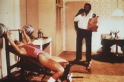 Steve (Bud Spencer, r.) und seine Kollegin, die FBI-Agentin Irene (Jackie Castellano, l.), halten sich auf unterschiedliche Weise fit: Steve isst w&auml;hrend Irene trainiert ...