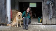 Sophie Berger sitzt mit Hund vor dem Stall.