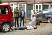 Die Kommissare Finn (Sven Martinek, l.) und Lars (Ingo Naujoks, 2.v.l.) kommen an den Tatort, an dem der Musiker Kai Scherer (Zio Tristan Mundry, liegend) am helllichten Tag erschossen wurde. Rechtsmediziner Dr. Henning Strahl (Christoph Tomanek, r.) hat mit seinem Team bereits die Projektile sichergestellt.