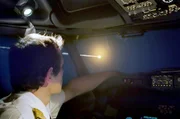 Ein Pilot betrachtet durch das Cockpit seines Flugzeugs die Flugbahn eines Asteroiden.