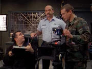 Emmett (Saul Rubinek, li.) und sein Team, Kameramann James (Tobias Slezak, re.) und Tontechniker Wickenhouse, machen weiter mit ihren Interviews. Col. Rundell (Mitchell Kosterman, mi.) &uuml;berwacht die Dreharbeiten...