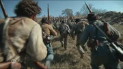 Das Bild zeigt eine Gruppe bewaffneter Personen in historischen Uniformen, die einen H&uuml;gel hinaufl&auml;uft und auf eine gr&ouml;&szlig;ere Formation vor ihnen zust&uuml;rmt.