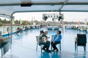 Shahzad Ismaily (li.) und Ganavya Doraiswamy (re.), im Hintergrund die Industrieanlagen von Leverkusen. Die Triennale findet gr&ouml;&szlig;tenteils auf einem in Monheim vor Anker liegenden Rheinschiff statt.