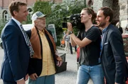 PR-Chef Bach (Knut Berger, li.) und Ex-Komiker Franz Damovsky (Michael Gwisdek) genie&szlig;en das Medieninteresse und beantworten die Fragen von einem TV-Reporter (Jan Hasenfu&szlig;, re.).