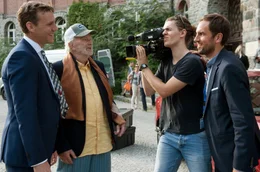 PR-Chef Bach (Knut Berger, li.) und Ex-Komiker Franz Damovsky (Michael Gwisdek) genie&szlig;en das Medieninteresse und beantworten die Fragen von einem TV-Reporter (Jan Hasenfu&szlig;, re.).