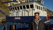 Captain Jake Anderson stands in front of his boat, the Saga, at dock.
