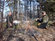 Stan Zuray (L) and Charlie Wright (R) take a break from beaver trapping to warm up and have something to eat.