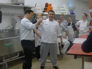 Buddy and Joey tap the beer cake, decorators watch in amusement.