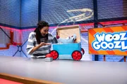 Woozle (re.) m&ouml;chte am gro&szlig;en Preis von Woozlingen teilnehmen und daf&uuml;r ein umweltfreundliches Rennauto erfinden. Doch das ist gar nicht so einfach, denn Woozles Ideen sind wie immer: komplett verr&uuml;ckt. Zum Gl&uuml;ck h&auml;lt Maria (li.) ein paar gute Ideen bereit.