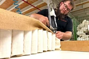 Ein Mitarbeiter heftet den Taschenfederkern f&uuml;r das Boxspringbett zusammen.