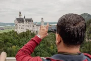 Touristen stehen auf der Marienbr&uuml;cke vor dem Schloss Neuschwanstein.