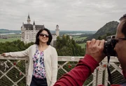 Touristen posieren auf der Marienbr&uuml;cke vor der Neuschwanstein-Kulisse.