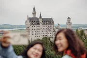 Touristen posieren auf der Marienbr&uuml;cke vor der Neuschwanstein-Kulisse.