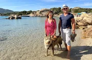 Britta (l) und Andreas spazieren mit ihrem Picard Toni am Strand von Sardinien.