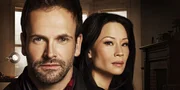 L-R: Sherlock Holmes (Jonny Lee Miller), Joan Watson (Lucy Liu).