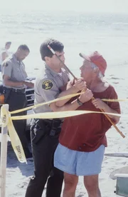 Leo (Leo Penn, r.) und ein Polizist streiten sich am Strand.