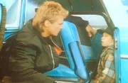 Tommy Wiley (Kaj-Erik Eriksen, r.) will nicht mit den Au&szlig;erirdischen verreisen. MacGyver (Richard Dean Anderson, l.) versucht, den Kleinen zu beruhigen.