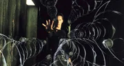 Neo (Keanu Reeves) h&auml;lt in der Matrix seine H&auml;nde hoch, um die herannahenden Gew&auml;hrkugeln in Zeitlupengeschwindigkeit zu bringen, damit er ihnen ausweichen kann.