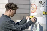Ein Mitarbeiter der Organisation SHARE beim Befestigen von Aufklebern, die auf die Video&uuml;berwachung in Belgrad aufmerksam machen sollen