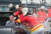 Notarzt Haase (Fabian Harloff, M.) versorgt einen Schwerverletzten (Komparse), während die Kollegen der Feuerwehr (Komparsen), ihn aus dem Auto befreien. Besorgt steht dessen Begleiterin Sandra (Natalia Rudziewicz, hinten) daneben. Notarzt Haase (Fabian Harloff, M.) versorgt einen Schwerverletzten (Komparse), während die Kollegen der Feuerwehr (Komparsen), ihn aus dem Auto befreien. Besorgt steht dessen Begleiterin Sandra (Natalia Rudziewicz, hinten) daneben.