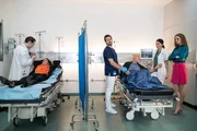 Dr. Jan K&uuml;hnert (Marc Dumitru, l.) k&uuml;mmert sich um die Kopfverletzung von Ex-Ehefrau Claudia Ott (Berrit Arnold, 2.v.l.). Zur gleichen Zeit behandeln Pfleger Karim (Nassim Avat, 3.v.l.) und Dr. Leonie Mertens (Linda Marlen Runge, 2.v.r.) den Gesch&auml;ftsmann Kai Ott (Simon Licht, 3.v.r.). Seine neue Ehefrau Sophie Ott (Nora Huetz, r.) steht ver&auml;rgert bei ihm.