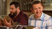 Die Kollegen Yann (Guy Lecluyse, li.) und Antoine (Dany Boon) versuchen beim gemeinsamen Abendessen ihrem Chef Philippe den &ouml;rtlichen Dialekt Ch&rsquo;ti beizubringen.