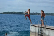 Ole filmt sich beim Sprung ins Wasser, Nils und Robin machen sich sprungbereit.