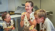Fini, Leo und Paulina beim Verkosten von Lebkuchenherzen. Sie finden heraus, warum der Lebkuchen f&uuml;r Pilgerinnen und Pilger ein wichtiger Proviant ist.