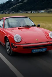 Auf dem Bild ist ein klassischer roter Porsche 911 zu sehen.