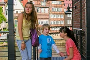 Bei einer St&auml;dtetour durch die L&uuml;neburger Altstadt begegnen Ally (Marny Kennedy, li.) und Jackie (Charlotte Nicdao, re.) einem kleinen Jungen (Jordy Wortmann), der sich verlaufen hat.