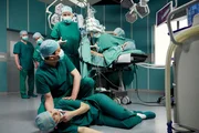 Dr. Kathrin Globisch (Andrea Kathrin Loewig, liegend) bricht w&auml;hrend einer Operation pl&ouml;tzlich zusammen. Dr. Roland Heilmann (Thomas R&uuml;hmann, stehend, 3.v.re.) bittet Dr. Philipp Brentano (Thomas Koch, kniend), sich um Kathrin zu k&uuml;mmern und ihn w&auml;hrend der weiteren OP auf dem Laufenden zu halten.  Weitere: Komparsen