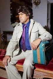 Ein Mann sitzt und h&auml;lt einen Koffer in der Hand