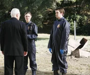 Als Brennan (Emily Deschanel, M.) und Zack (Eric Millegan, r.) von Pfarrer William Donlan (George Coe) gebeten werden, nach einem Wasserrohrbruch auf einem alten Friedhof einige aufgeschwemmte Leichen zu untersuchen, entdecken sie den Sch&auml;del eines Mannes, der erst vor Kurzem beerdigt worden ist.