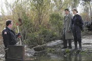 Booth (David Boreanaz, 2.v.r.) und Brennan (Emily Deschanel) untersuchen den Tatort, an dem eine Frau - ohne Knochen und in einer Kiste verpackt - im Fluss gefunden wurde.